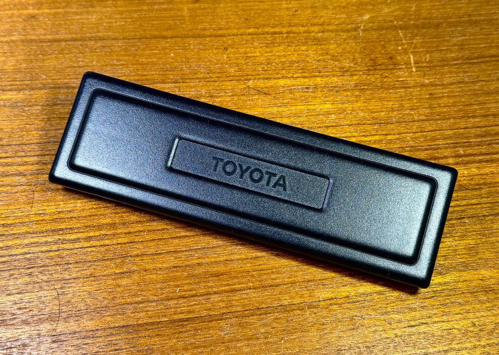 NOS OEM TOYOTA FULL SIZE Single DIN. RADIO TUNER , CONSOLE BOX OPENING DELETE  TOYOTA Bold LOGO Combined with a Picture Frame Layout   COVER PLATE